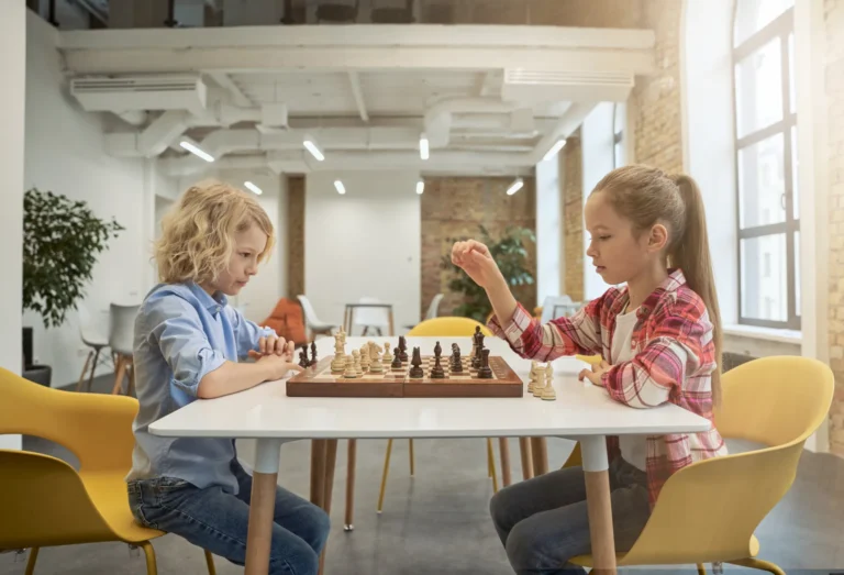 two_smart_little_children_boy_girl_developing_chess_strategy_playing_board_game_sitting_1